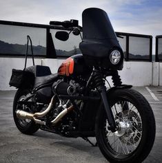 a black motorcycle parked in a parking lot next to a building with windows on the side