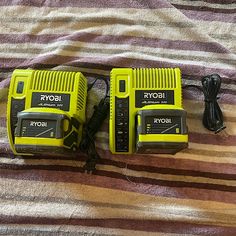 two yellow and black radio remotes sitting on top of a striped bed sheet next to each other