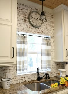 a kitchen with white cabinets and a clock on the wall above the sink in front of the window