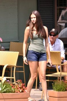 a woman in short shorts is walking on the sidewalk