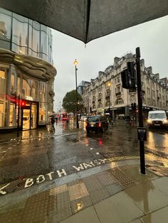 a wet city street with cars driving down it