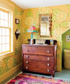 a dresser and mirror in a room with flowers on the wall