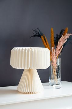 two vases sitting on top of a white table next to each other with flowers in them