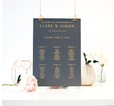 a wedding seating chart on a table with flowers and vases in front of it