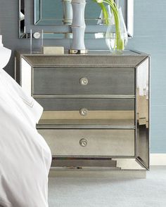 a bedroom with a mirrored dresser and flower vase on the nightstand next to the bed