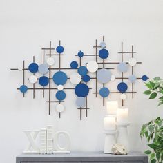 a white vase sitting on top of a table next to a wall sculpture with blue and white circles