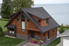 an aerial view of a house with flowers in the front yard and water in the background