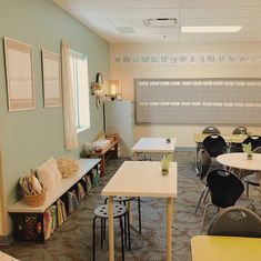 an empty classroom with tables, chairs and a chalkboard in the back ground area