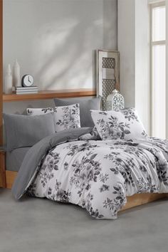 a bed with grey and white comforters in a room