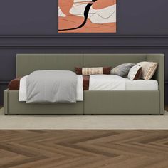 a bed sitting on top of a hard wood floor next to a wall mounted painting