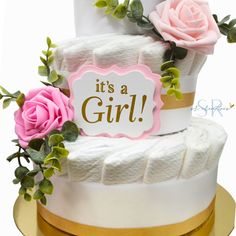 a white cake with pink roses on top and it's a girl sign