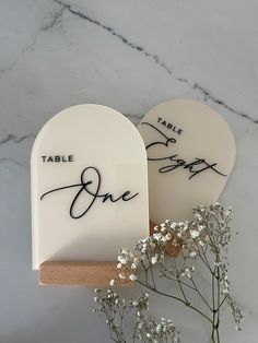 there are two white hearts with the words table one and one written on them next to some baby's breath flowers