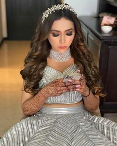 a woman sitting on the floor wearing a dress and holding a cell phone in her hands