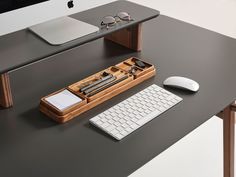 a computer desk with a keyboard, mouse and glasses on it next to an apple monitor