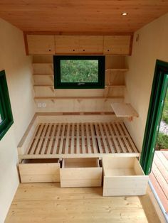 a small bedroom with wooden flooring and green windows