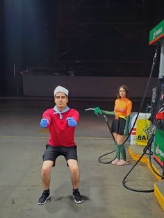 two people standing in front of a gas station with hoses attached to their hands