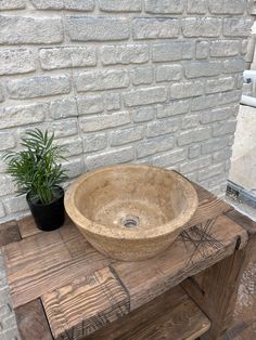 a wooden table with a stone sink and potted plant