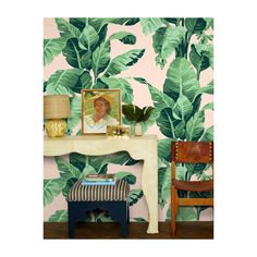 a living room with a table and chair in front of a plant wallpapered wall