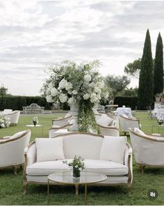 a bunch of couches and chairs sitting on top of a grass covered field with flowers