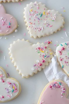 decorated cookies with sprinkles and frosting arranged on a white tablecloth