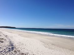 an empty beach with blue water and white sand