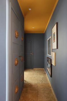 an empty hallway with blue walls and pictures on the wall, along with two doors