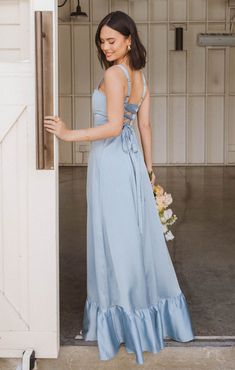 a woman in a blue dress is standing by the door