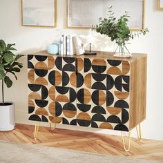 a wooden cabinet with black and gold designs on the front, next to a potted plant