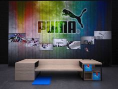 a wooden bench sitting in front of a wall with pictures on it and the word puma painted on it