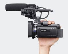 a hand holding a video camera with a microphone attached to the back of it's arm