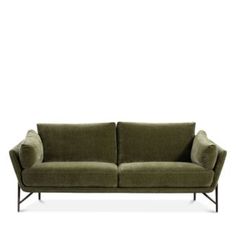 a green couch sitting on top of a white floor next to a black metal frame