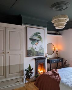 a bedroom with a bed, fireplace and painting on the wall next to an armoire