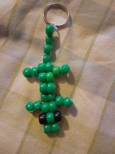 a green and black beaded keychain sitting on top of a bed