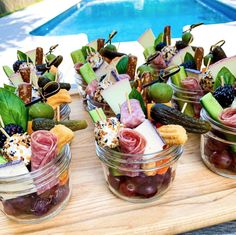 small jars filled with food sitting on top of a wooden table next to a swimming pool