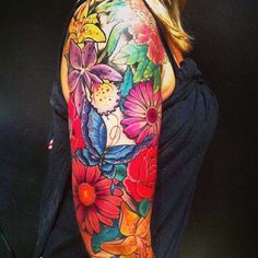 a woman's arm with colorful flowers and butterflies on her left shoulder, which is covered in tattoos