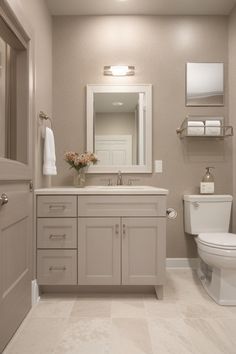 a white toilet sitting next to a sink in a bathroom under a mirror and lights