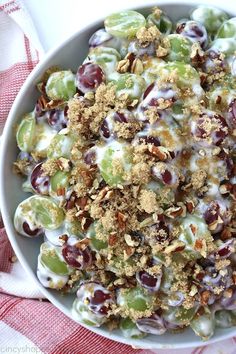 a bowl filled with grapes and nuts on top of a red and white checkered cloth