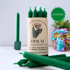 green candles sitting on top of a white counter next to a skull and an air plant