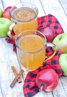 two mugs filled with apple cider on top of a table