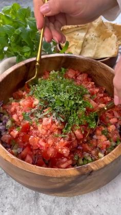 a wooden bowl filled with salsa and tortilla chips on top of a table