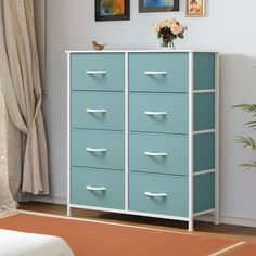 a blue and white cabinet with drawers in a living room next to a painting on the wall