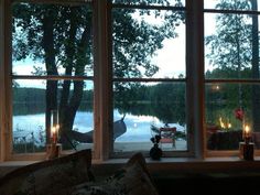 two windows with candles lit in front of them, overlooking a lake and trees at night