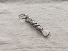 a metal bottle opener sitting on top of a white cloth covered table next to a pair of scissors