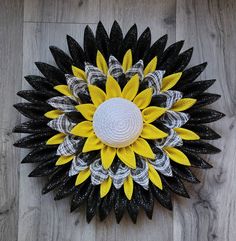 a black, white and yellow sunflower on a wood floor