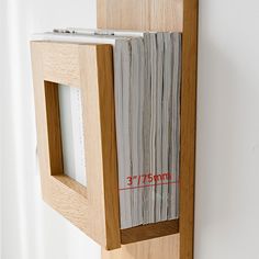 a wooden frame holding several files and a tape measure on the bottom half of it