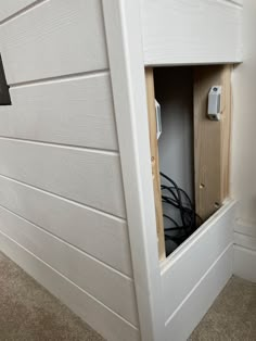 an electrical outlet in the corner of a white wall with wood paneling on it