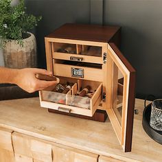 a person is opening the door to a small wooden cabinet with wine glasses in it