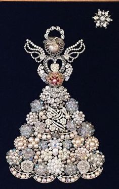 an elaborate christmas tree made out of pearls and other jeweled objects is displayed in a wooden frame