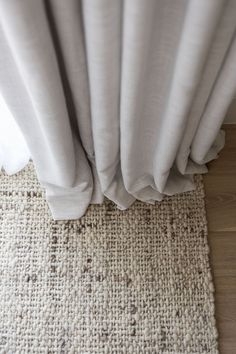 a close up of a white curtain on top of a wooden floor