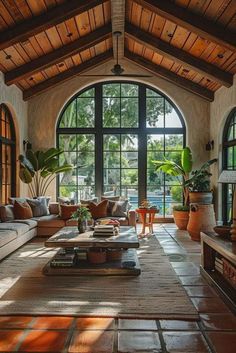 a living room filled with lots of furniture next to large windows and potted plants